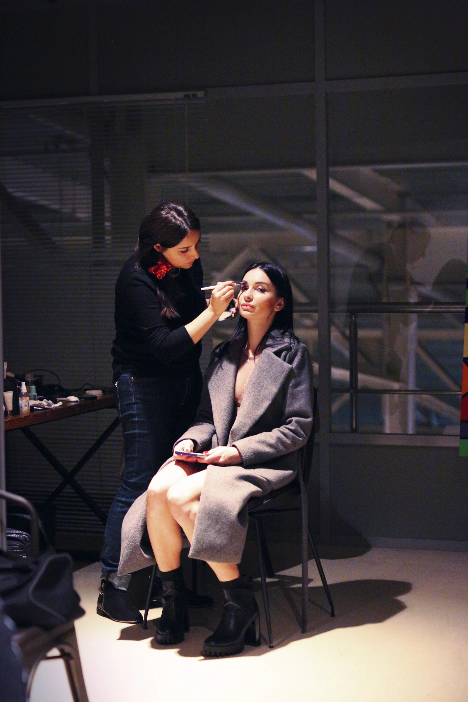 Make-up artist al lavoro mentre trucca una cliente in studio, luce calda