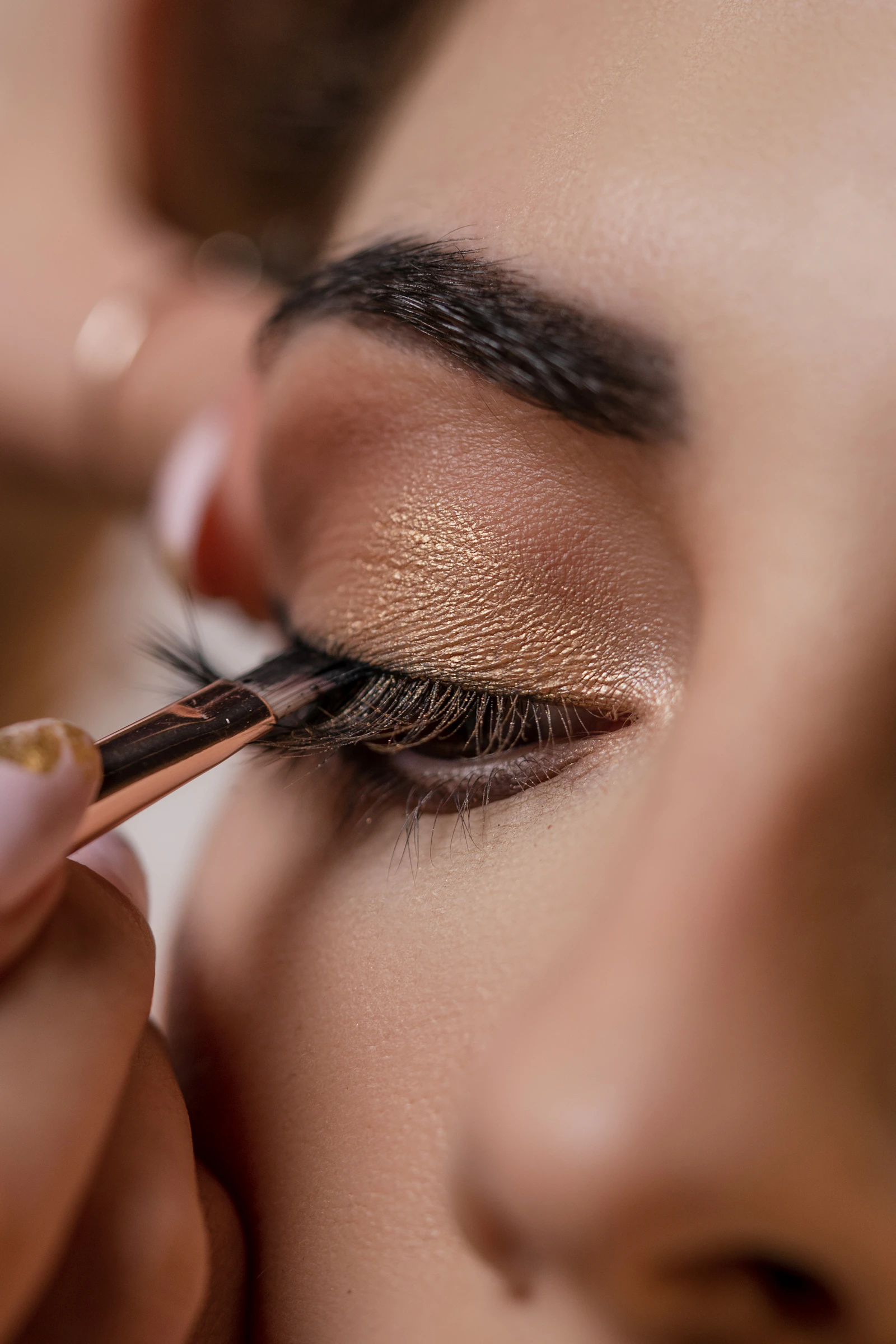Primo piano dell'applicazione di un ombretto dorato durante un trucco professionale